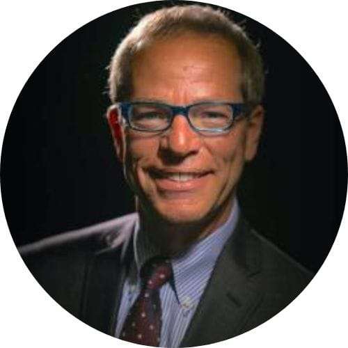 Top futurist keynote speakers: a man wearing glasses and a suit smiles in front of a black background.