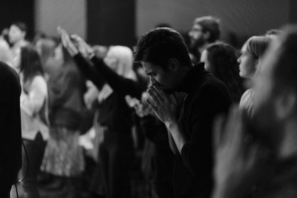 A group of emotional audience standing up while listening to speakers at a Christian event.