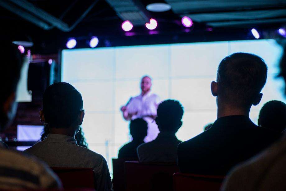 A Christian speaker on stage with an attentive audience listening to him.