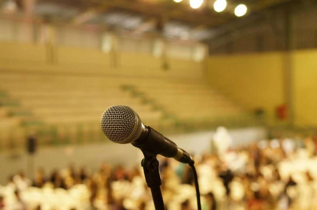 A microphone in the foreground with a blurred background of a huge audience.